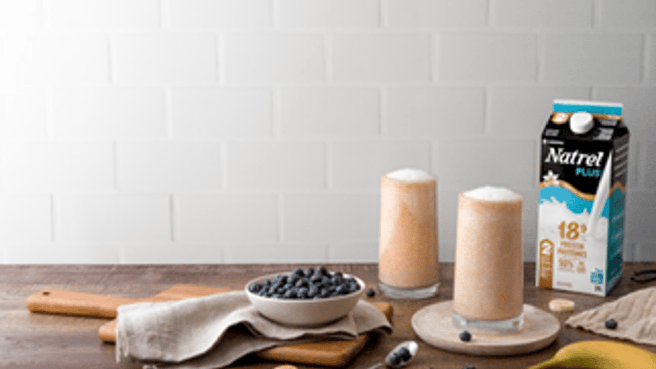 Carton of Natrel Plus Vanilla sitting on a table with two full glasses of milk