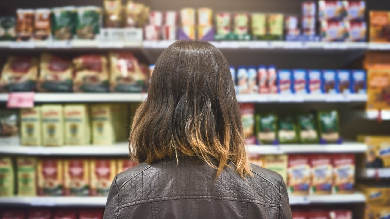 woman choosing between brands at a grocery store