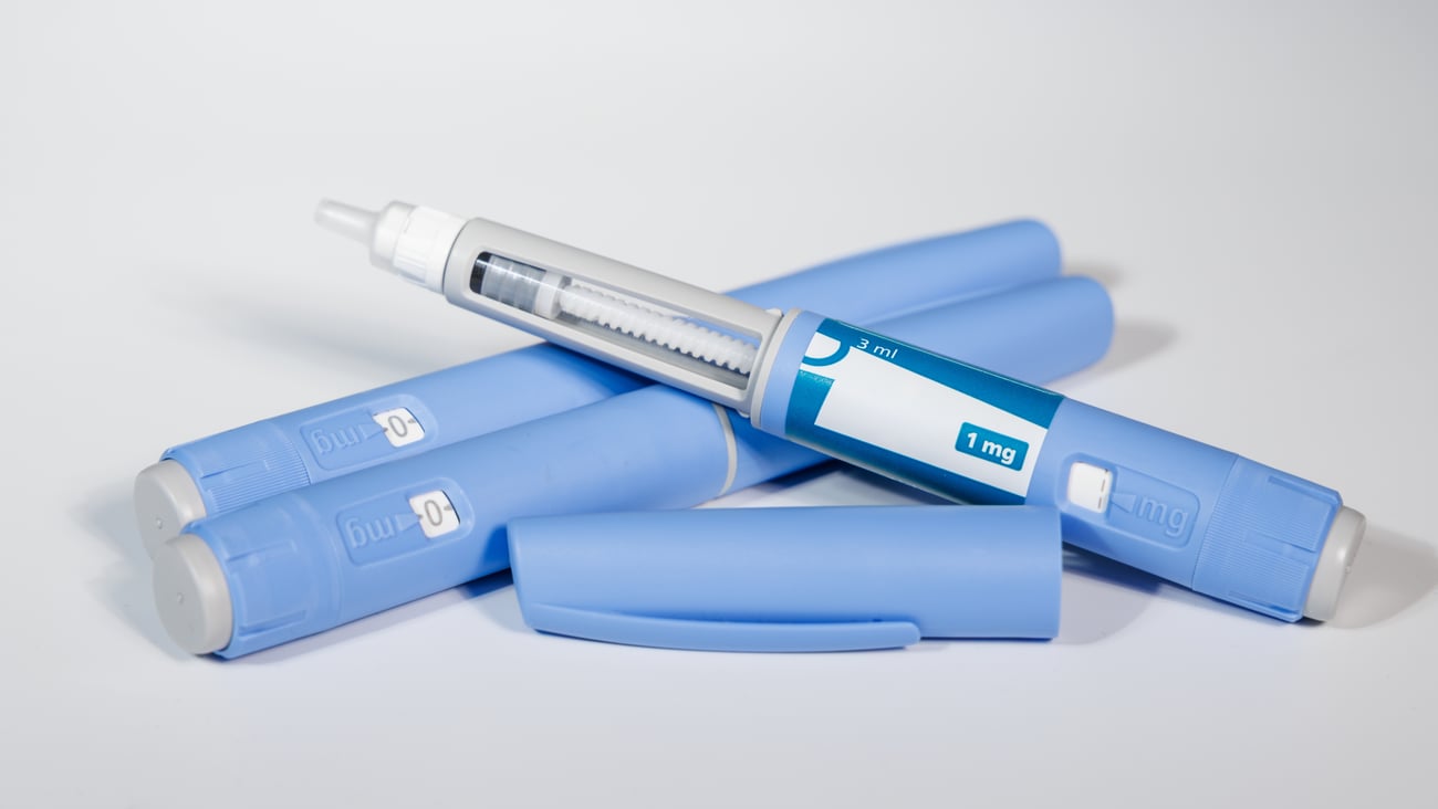 GLP-1 semaglutide injection pens with pills and measuring tape over white background illustrating health and prevention