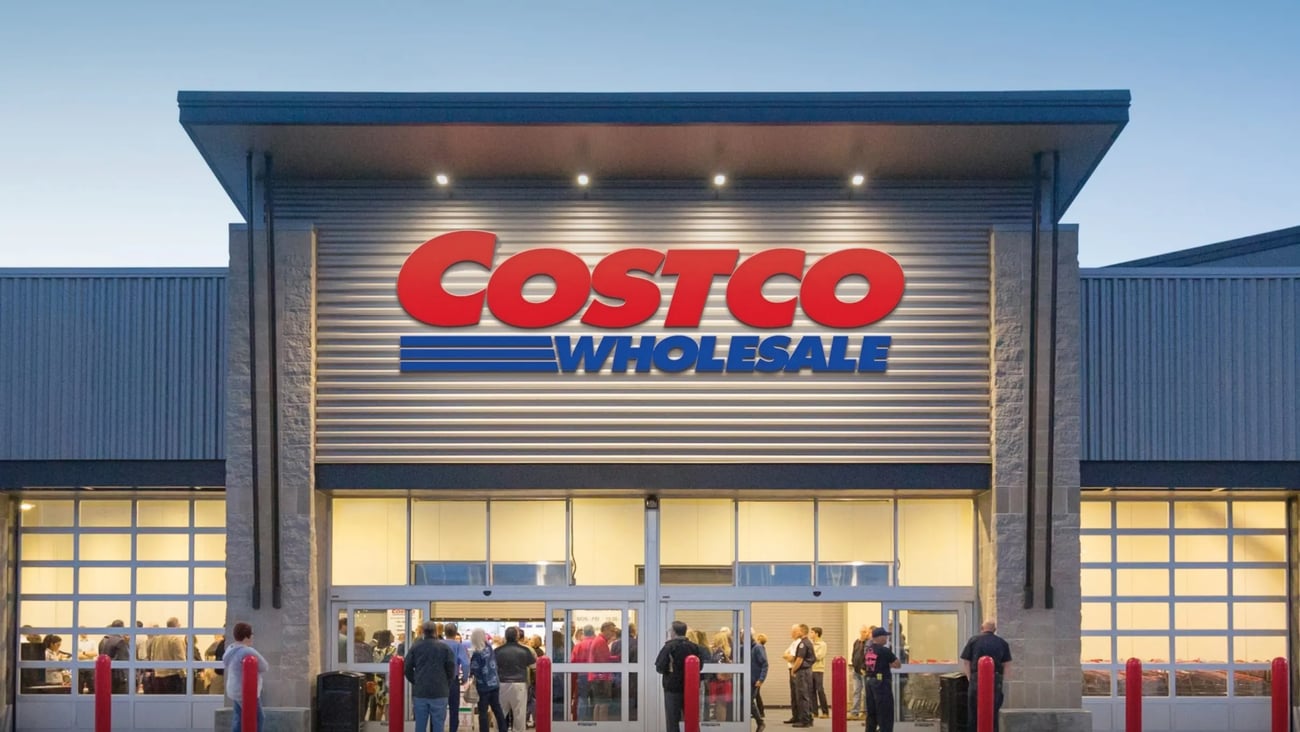 Outside shot of a Costco at night with people in the entrance way