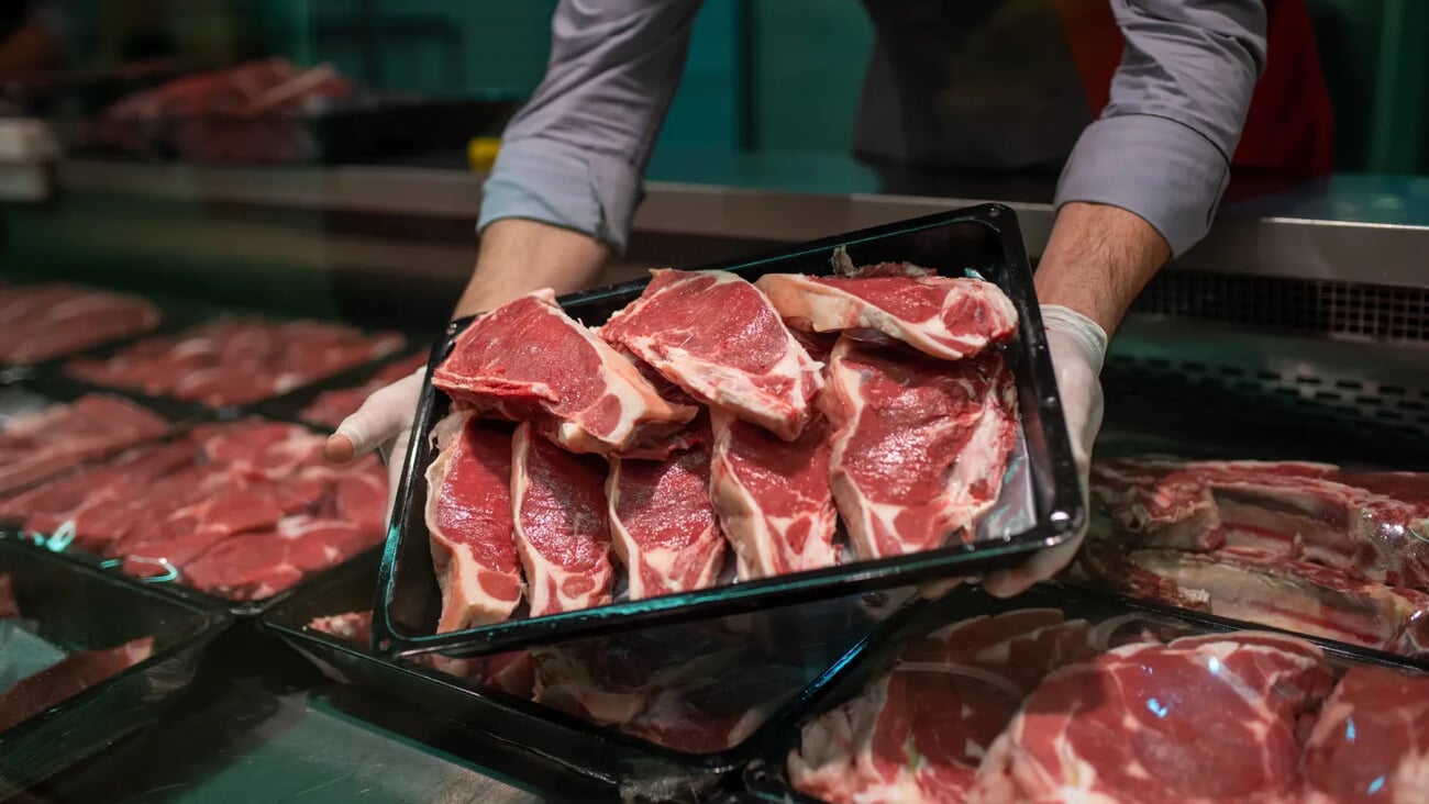 Closeup of butcher's hands holding meat piece in shop; Shutterstock ID 2450875827