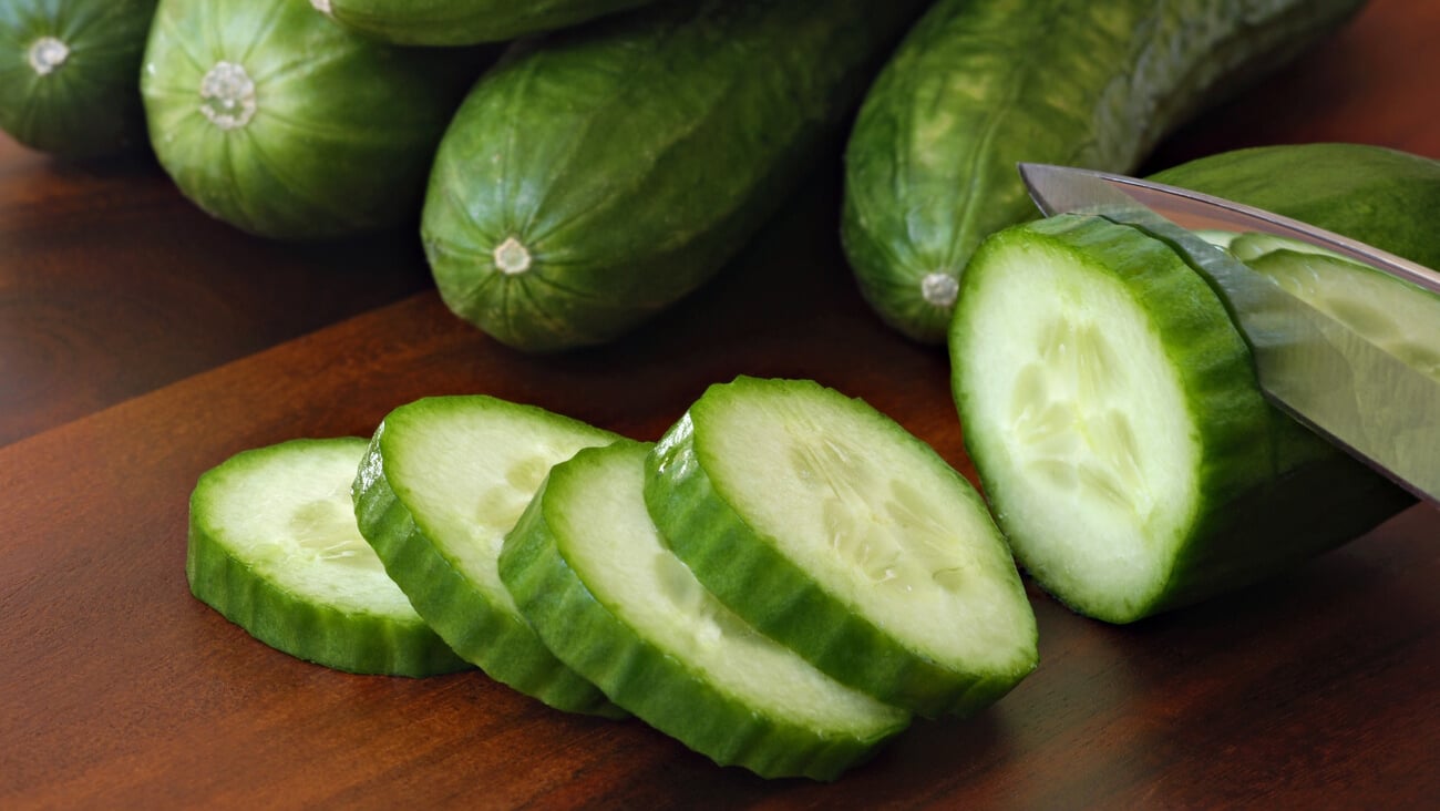 Freshly sliced mini cucumbers with knife on wooden cutting board.  Macro with shallow dof.  Focus on front slices.; Shutterstock ID 71318215