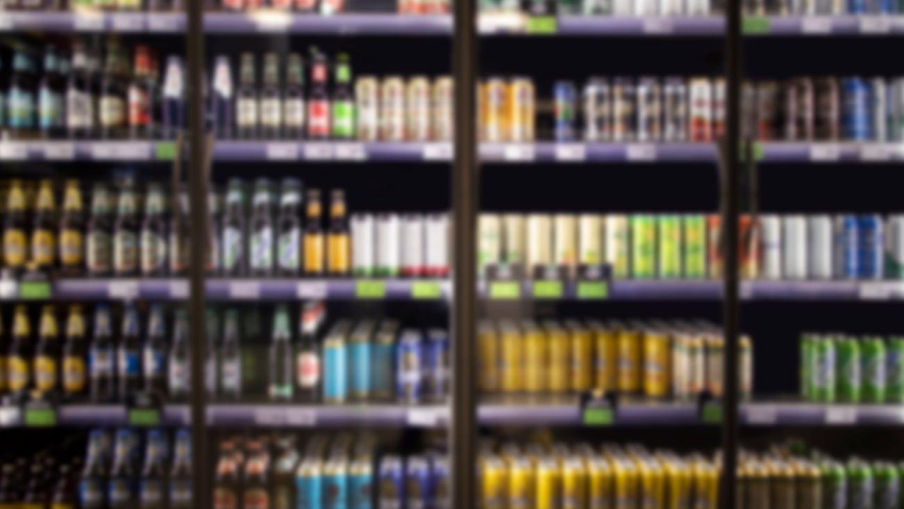 Alcohol and cold beverage in cooler at liquor store. Bottles and cans of alcohol drinks for sale.