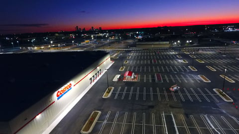 The outside of a Costco warehouse at sunset with a near empty parking lot