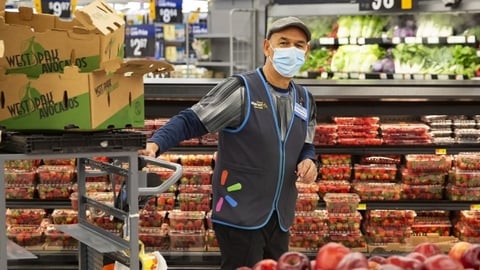 Walmart associated pulling a cart through the produce department