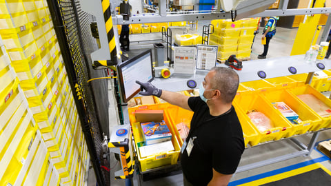 An Amazon employee wearing a face mask and filling orders