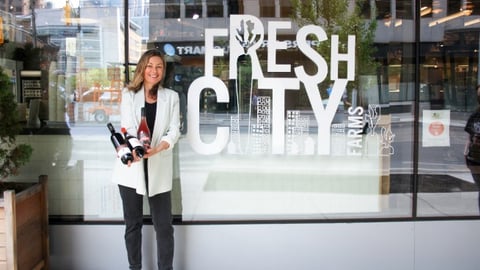 Head sommelier Jennifer Huether standing outside Fresh City holding a bottle of wine