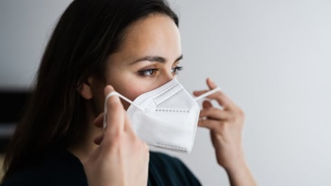 A woman putting on an N-95 mask