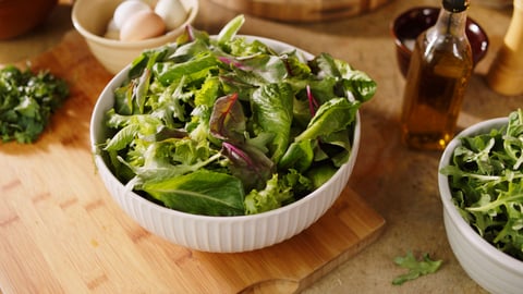 Plenty Farms' leafy greens in a salad bowl on a wooden table