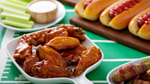 Table filled with Super Bowl party food including wings and hotdogs