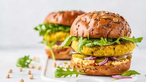 Two vegan burgers sitting on a white table 