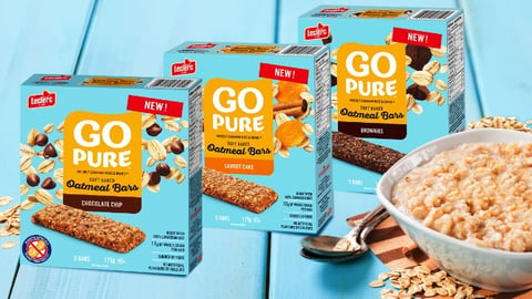 GO PURE Soft Baked Oatmeal Bars boxes on a blue table next to a bowl of oatmeal