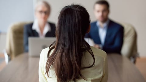 Businesswoman and businessman HR manager interviewing woman. Candidate female sitting her back to camera, focus on her, close up rear view, interviewers on background. Human resources, hiring concept