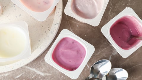 Composition with plastic cups with yogurt on grey table