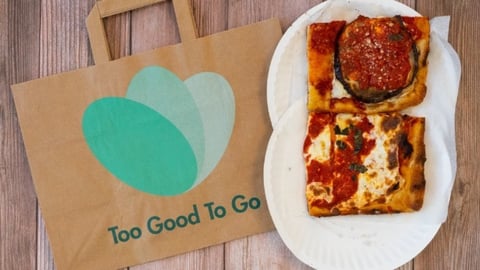 Too Good To Go paper bag next to two squares of pizza