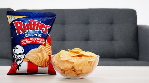 a bag of Ruffle chips beside a bowl of chips on a coffee table next 