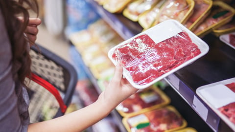 woman holding meat in a grocery store