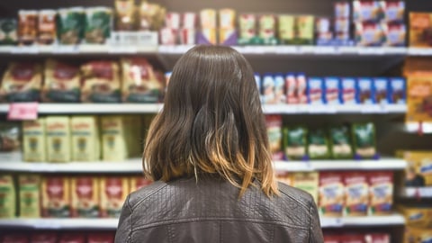 woman choosing between brands at a grocery store