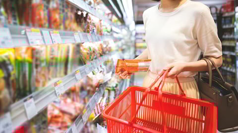 A woman with a shopping basked in a grocery store aisle