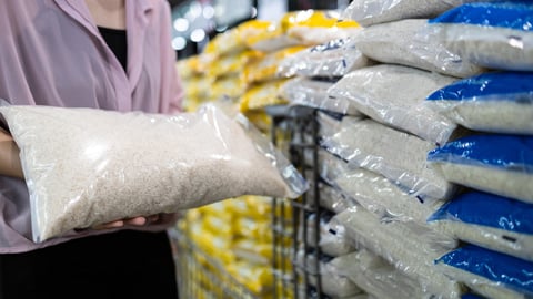 A female in a grocery store holding a bag of white rice