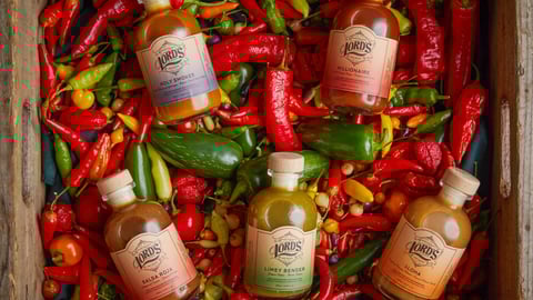 Bottles of Lord's Hot Sauce on a bed of peppers