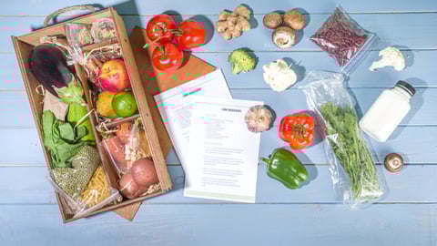 Meal-kit ingredients sitting next to a box on a wood blue table. Shutterstock Rimma Bondarenko