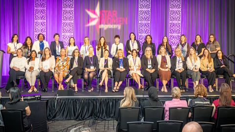 Two rows of women sitting on stage