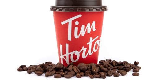 Tim Hortons coffee cup surrounded by beans