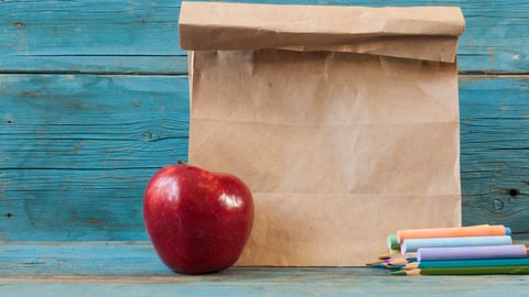 School lunch in a brown bag with an apple and chalk 