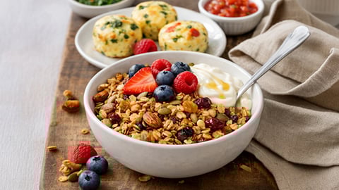 A bowl of cereal and granola, egg bites on a plate. Breakfast food items 