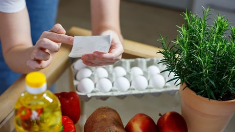 hands checking a grocery receipt above food on a counter
