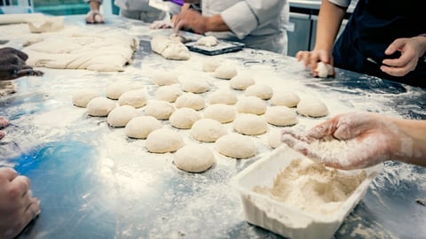 Hands rolling dough in flour