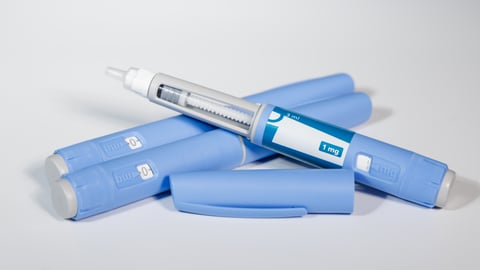 GLP-1 semaglutide injection pens with pills and measuring tape over white background illustrating health and prevention