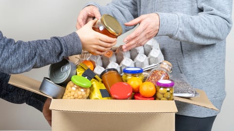 Volunteers hands putting grocery products, foodstuff to food donations box; Shutterstock ID 1868920810