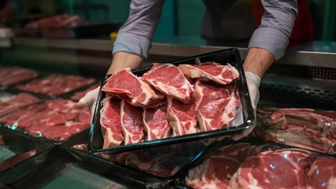 Closeup of butcher's hands holding meat piece in shop; Shutterstock ID 2450875827
