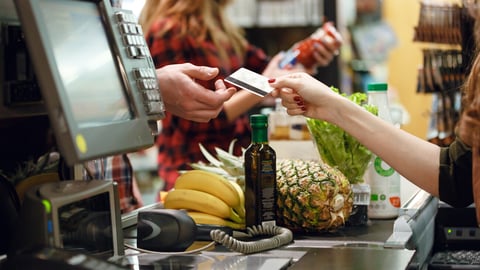 Cropped picture of young man gives credit card to cashier lady at workspace in supermarket.; Shutterstock ID 619563194