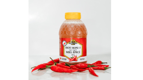 Bottle of Dutchman’s Gold Hot Honey surrounded by hot peppers