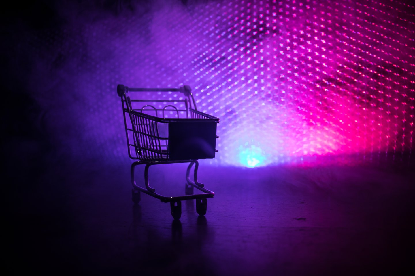 Empty shopping trolley on dark toned foggy background. 