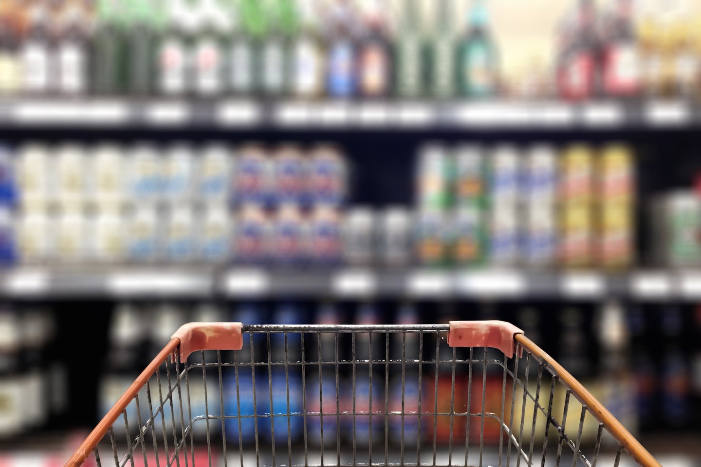 The end of a shopping cart facing a shelf of beer