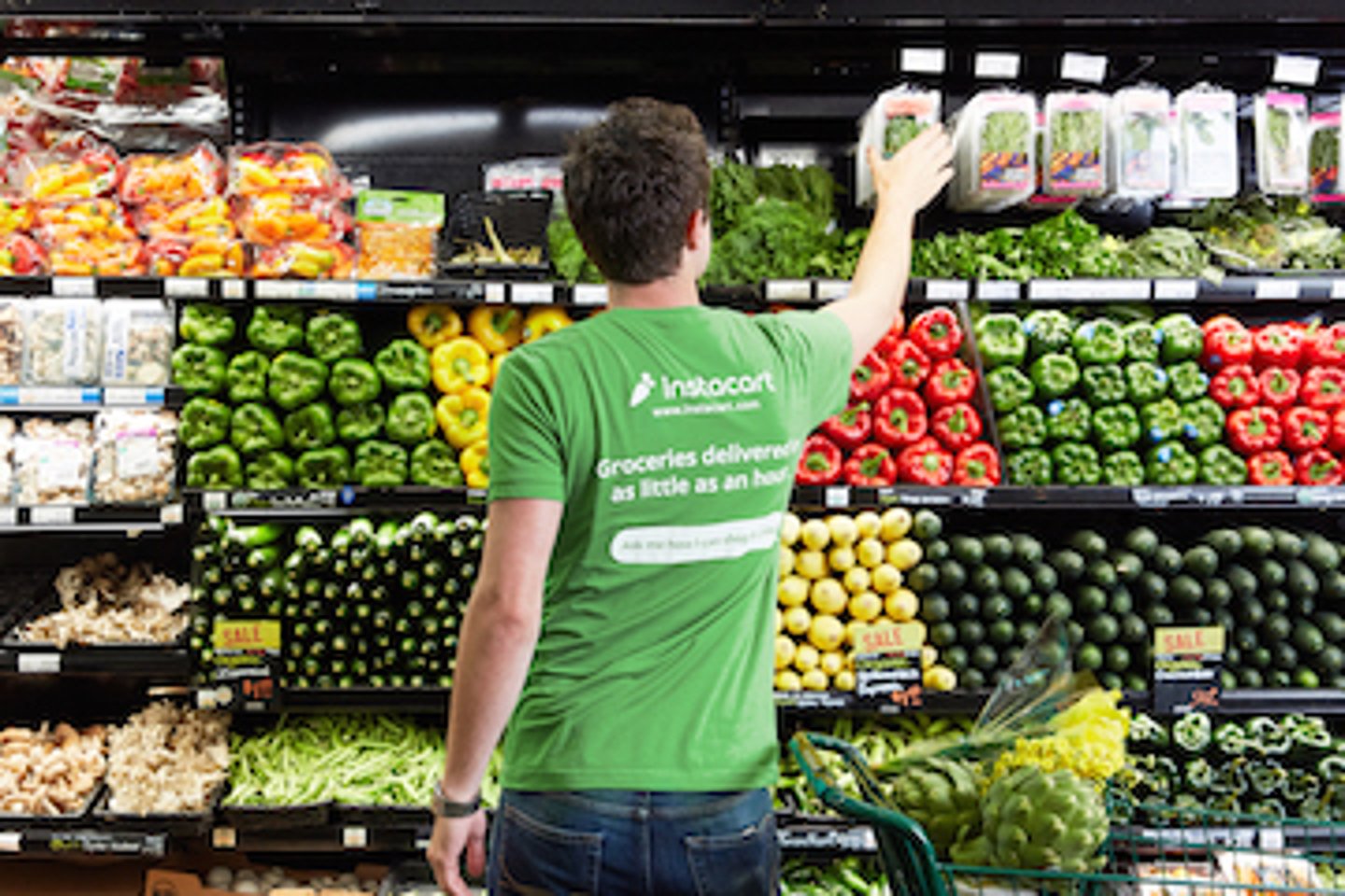 An Instacart shopper picking products from the produce section in a grocery store