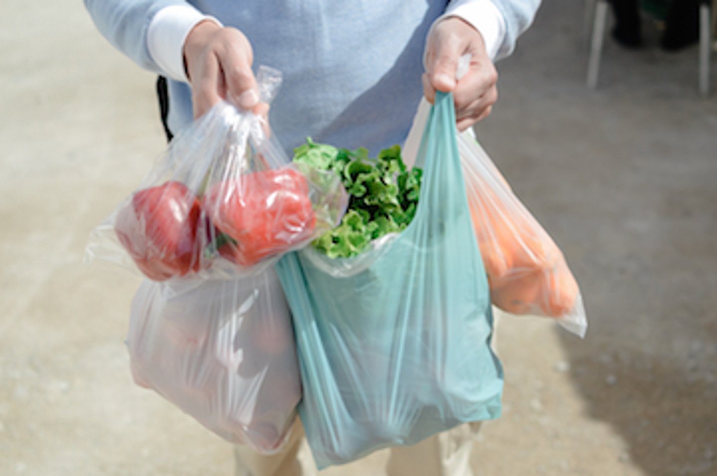 Person carrying plastic bags filled with groceries