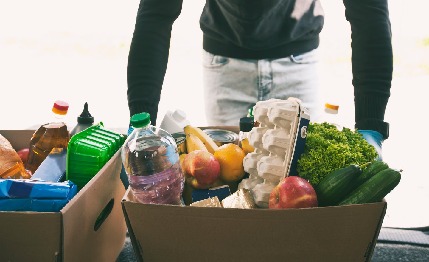 The courier takes the cardboard eco box with products from grocery shop out from the van