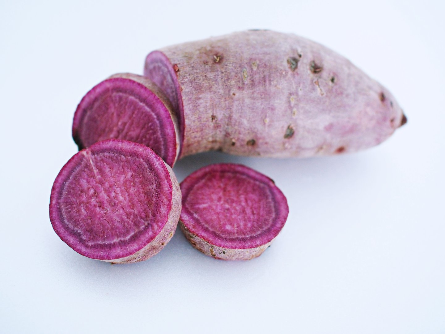 Close up view of sliced raw purple sweet potato isolated on white background