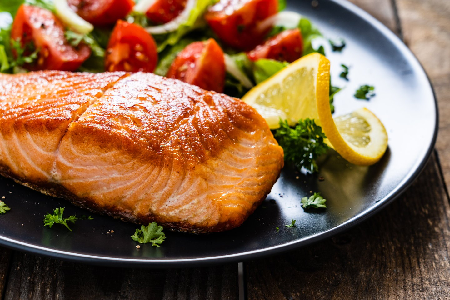 Fried salmon steaks with vegetables on wooden table