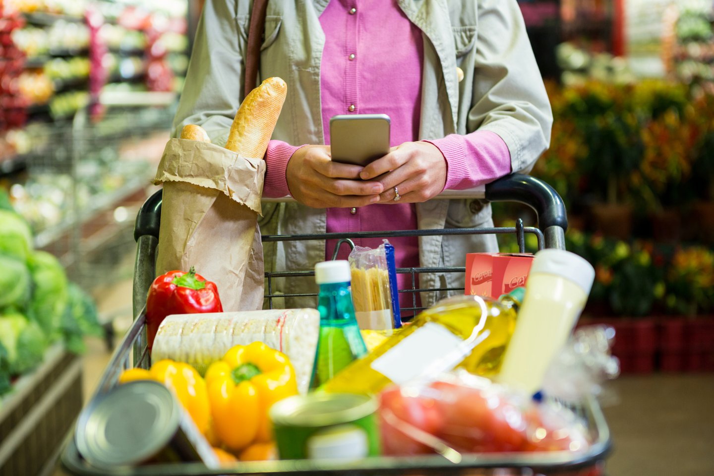 Woman using mobile phone while shopping in supermarket