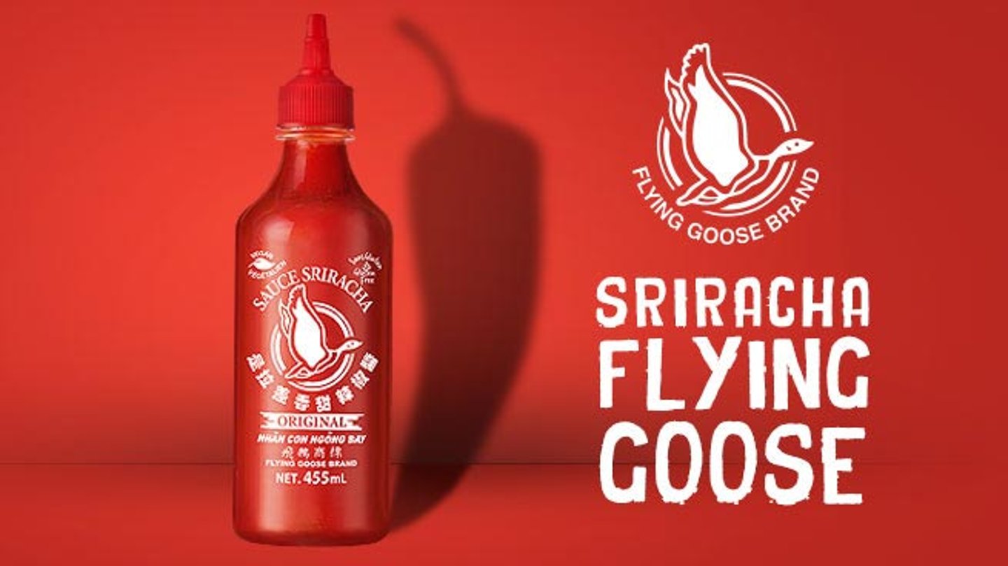 A bottle of Flying Goose Sriracha Original 455ml against a red background