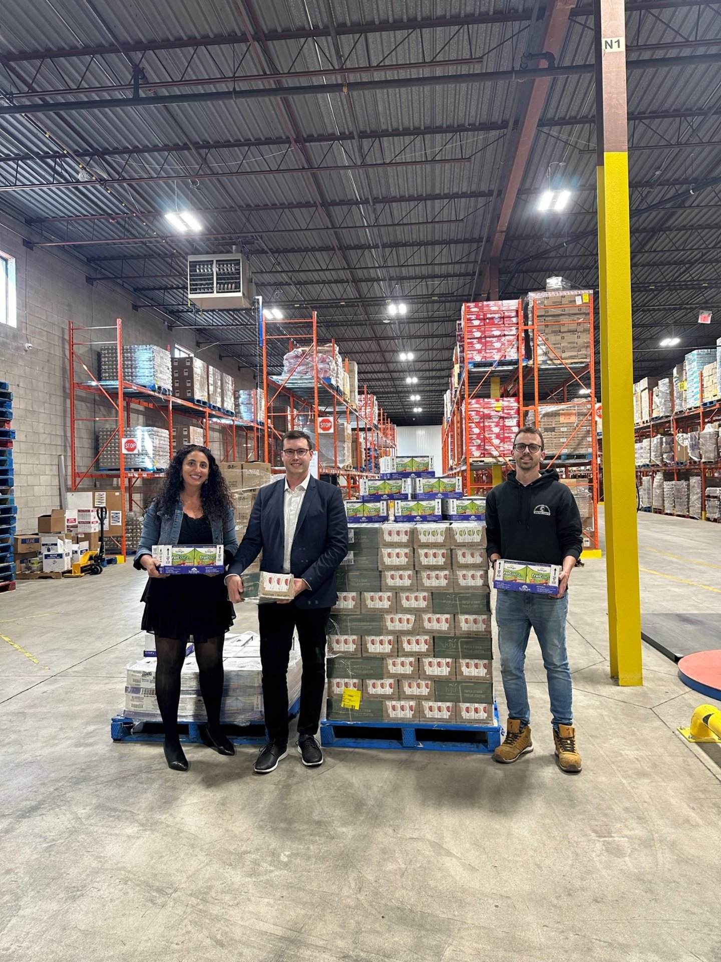 Rima Rabba, leader of the Rabba Roots Community Giving Program and Brandon Howell, Territory Manager at Lassonde deliver healthy snacks to Elliot Rate, Warehouse Supervisor at The Mississauga Food Bank just in time for the back-to-school season.