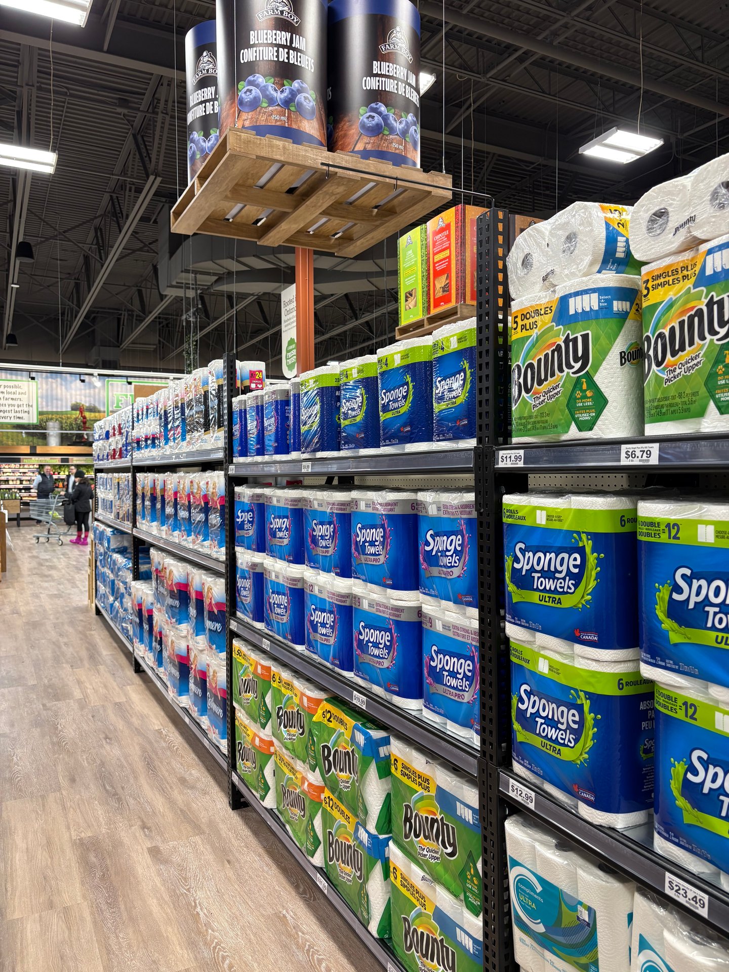 An aisle at the grocery store with shelves of paper towel and toilet paper