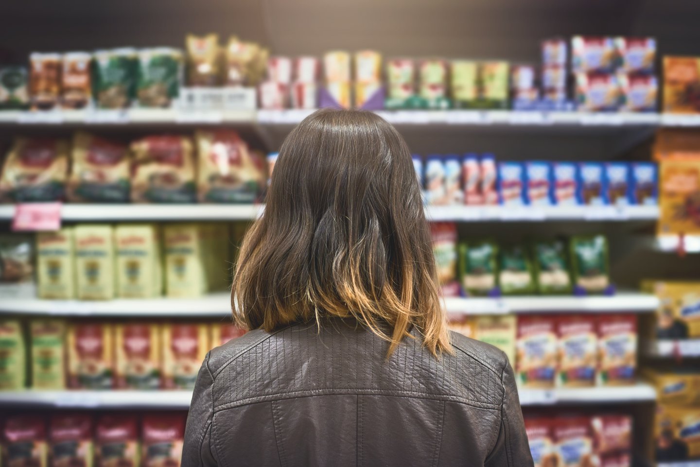 woman choosing between brands at a grocery store