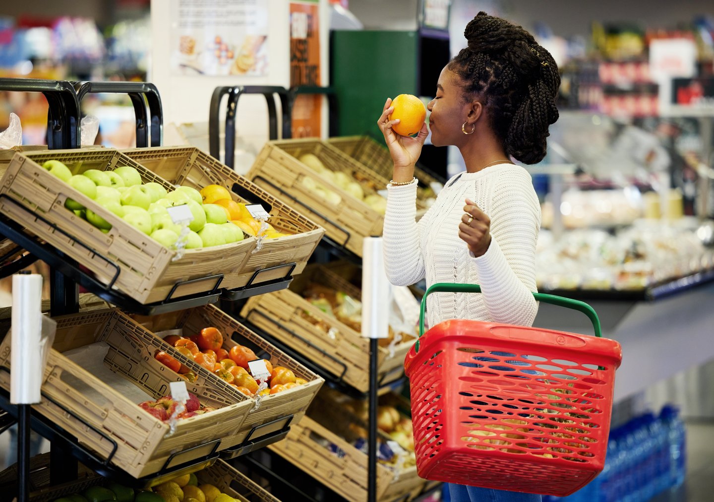 woman smelling an orange at the grocery store